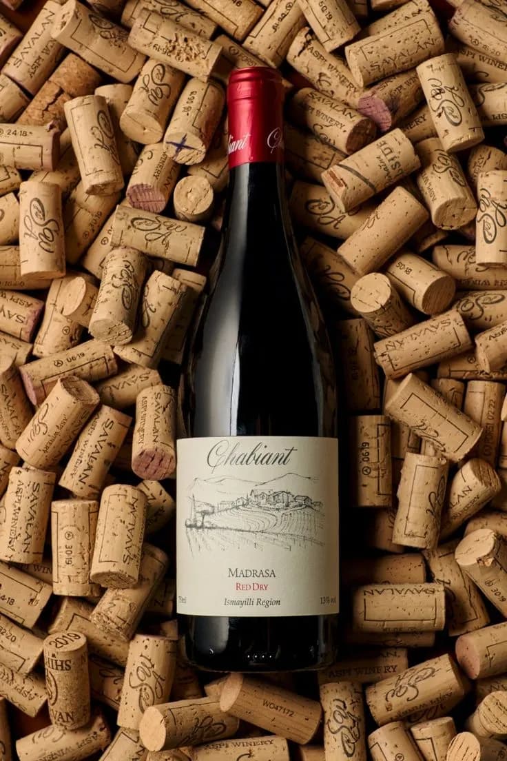 Bouteille de vin rouge posée sur un lit de bouchons de liège